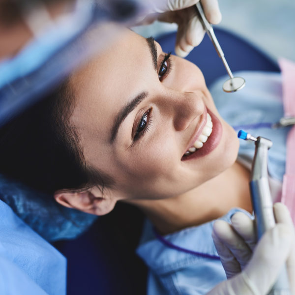 Oryx Customer Stories Close up of a smiling woman's face in a dental chair with a dentist holding dental tools