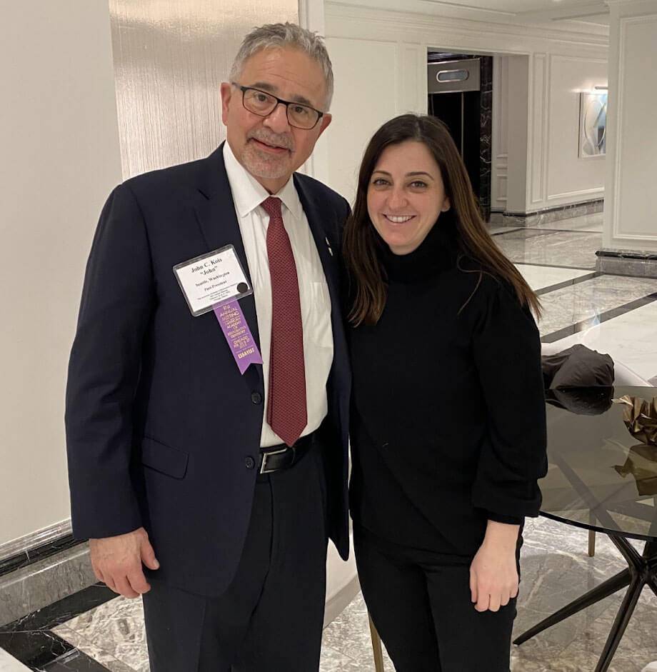 Dr. Rania Saleh stands smiling next to Dr. John C. Kois at a dental event, both posing for a photo indoors.