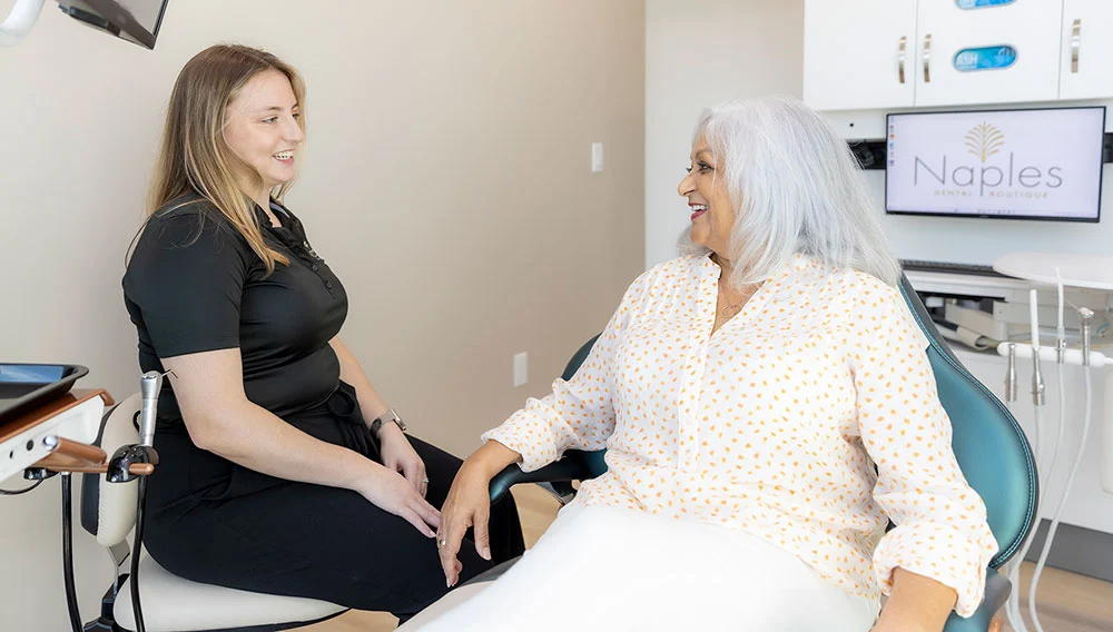 Hygienist Robyn Frey, RDH talking with a patient in a treatment room at Naples Dental Boutique